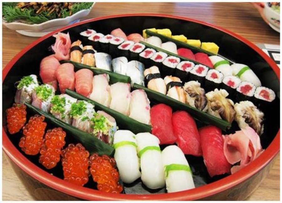 Cận cảnh bàn tay đang gắp một miếng sushi nigiri cá hồi bằng đũa, chuẩn bị thưởng thức tại nhà hàng ở Vạn Hạnh Mall. 